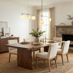 A nickel Clérachic chandelier lights a dining table with cream chairs in a room with a stone fireplace.