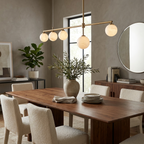 A brass Clérachic chandelier lights a dark wood dining table beneath a round mirror and boucle chairs.