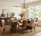 A black Clérachic chandelier glows above a dining table mixing leather and upholstered chairs beside a sunlit window.