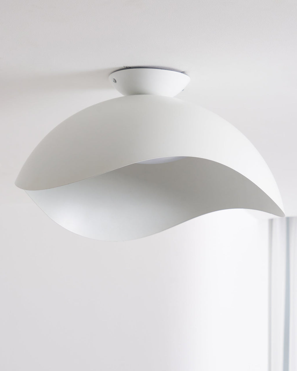 Seen from below near a window, the wave-cut underside of this Clérachic ceiling light lets soft light through.