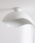 Seen from below near a window, the wave-cut underside of this Clérachic ceiling light lets soft light through.
