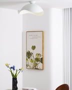 Mounted near a hallway corner, this Clérachic wave ceiling light glows warm beside a framed plant print.