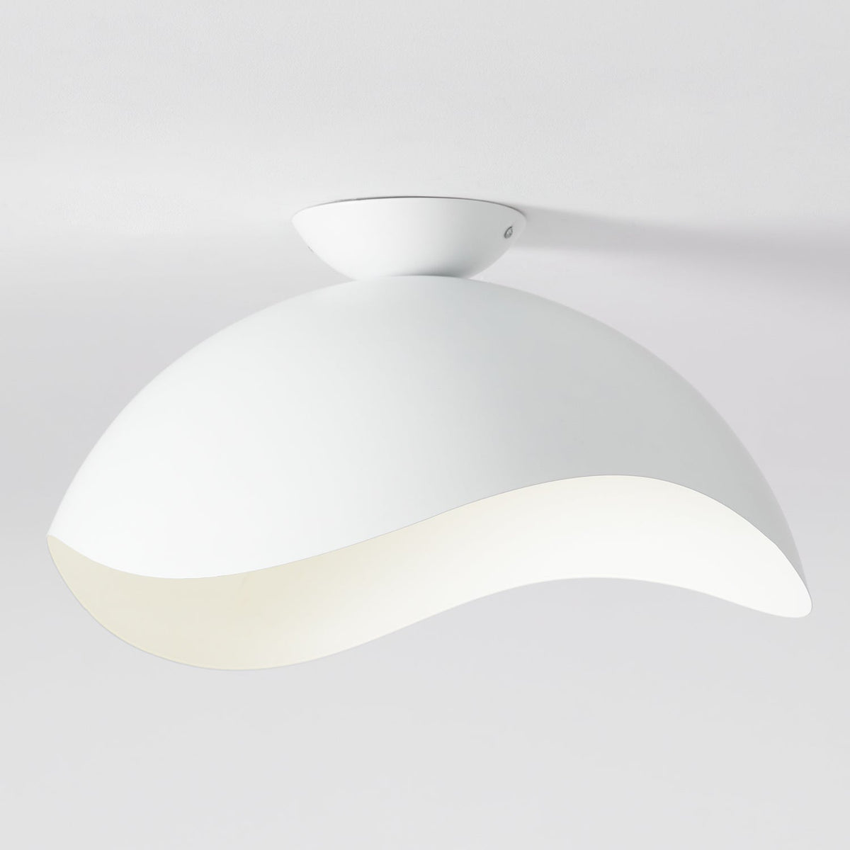 This Clérachic ceiling light in white shows its rounded canopy and curved wave shade against a pale wall.