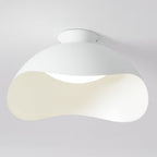 Close view of the wave-cut shade on this Clérachic ceiling light, with light spilling from the curved opening.