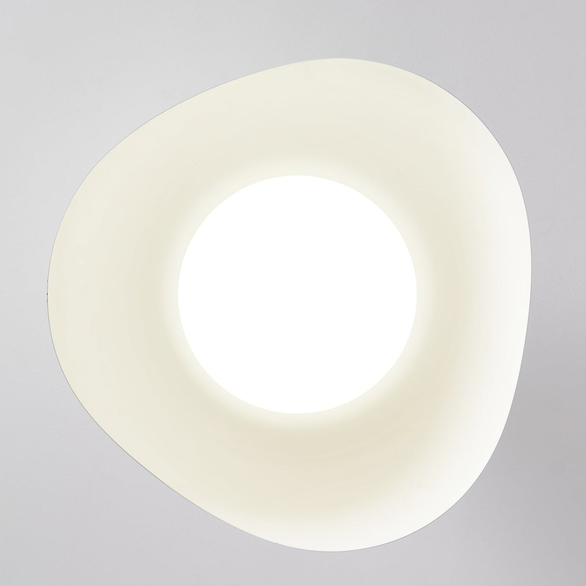 Looking straight up at this Clérachic ceiling light, its rounded wave-cut opening glows bright white.