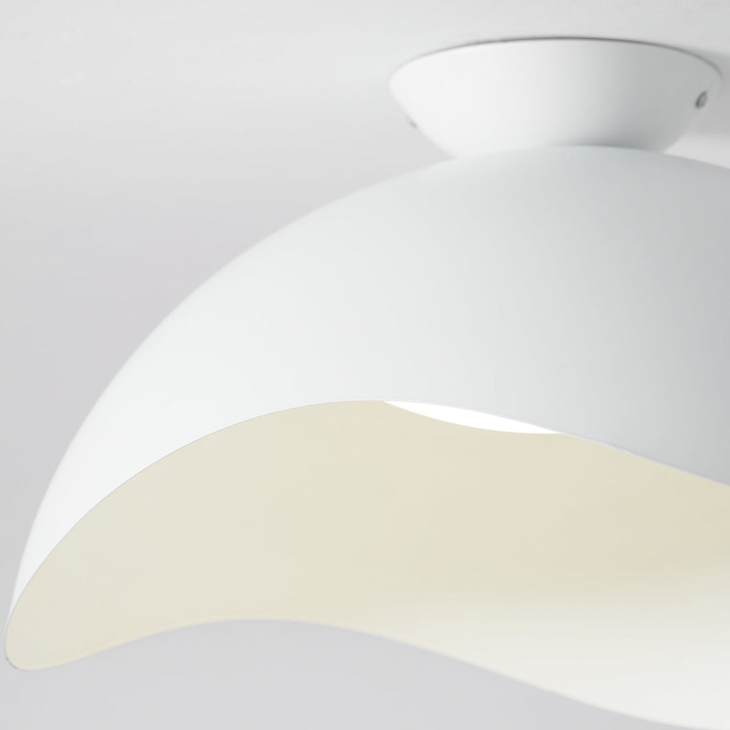 Close-up of the flowing wave-shaped shade on this Clérachic ceiling light, warm light tracing its curved edge.