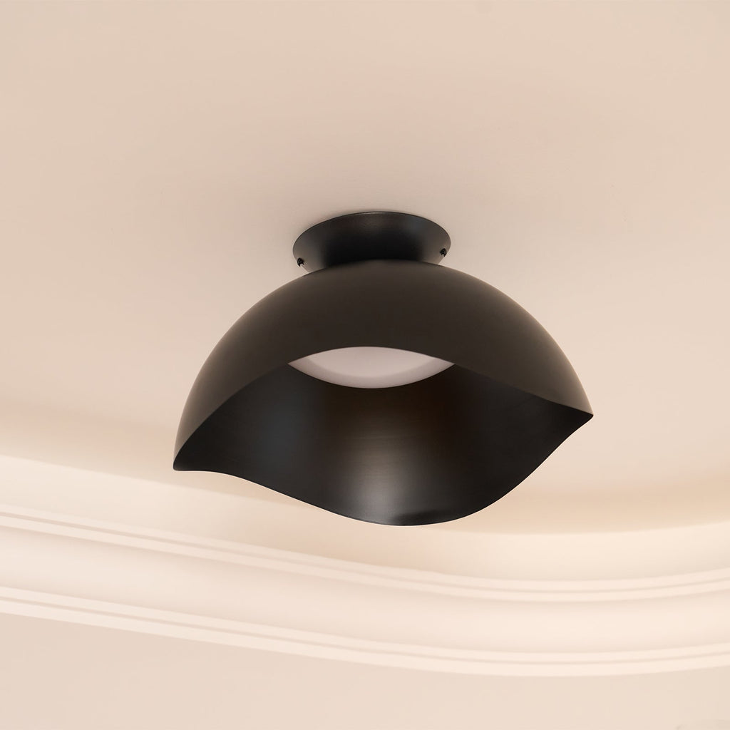Fitted beside ornate ceiling moulding, this Clérachic ceiling light in black stands out on a warm beige surface.