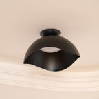 Fitted beside ornate ceiling moulding, this Clérachic ceiling light in black stands out on a warm beige surface.