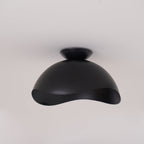 On a plain grey backdrop, this Clérachic ceiling light in black shows its full dome and wave-cut underside.