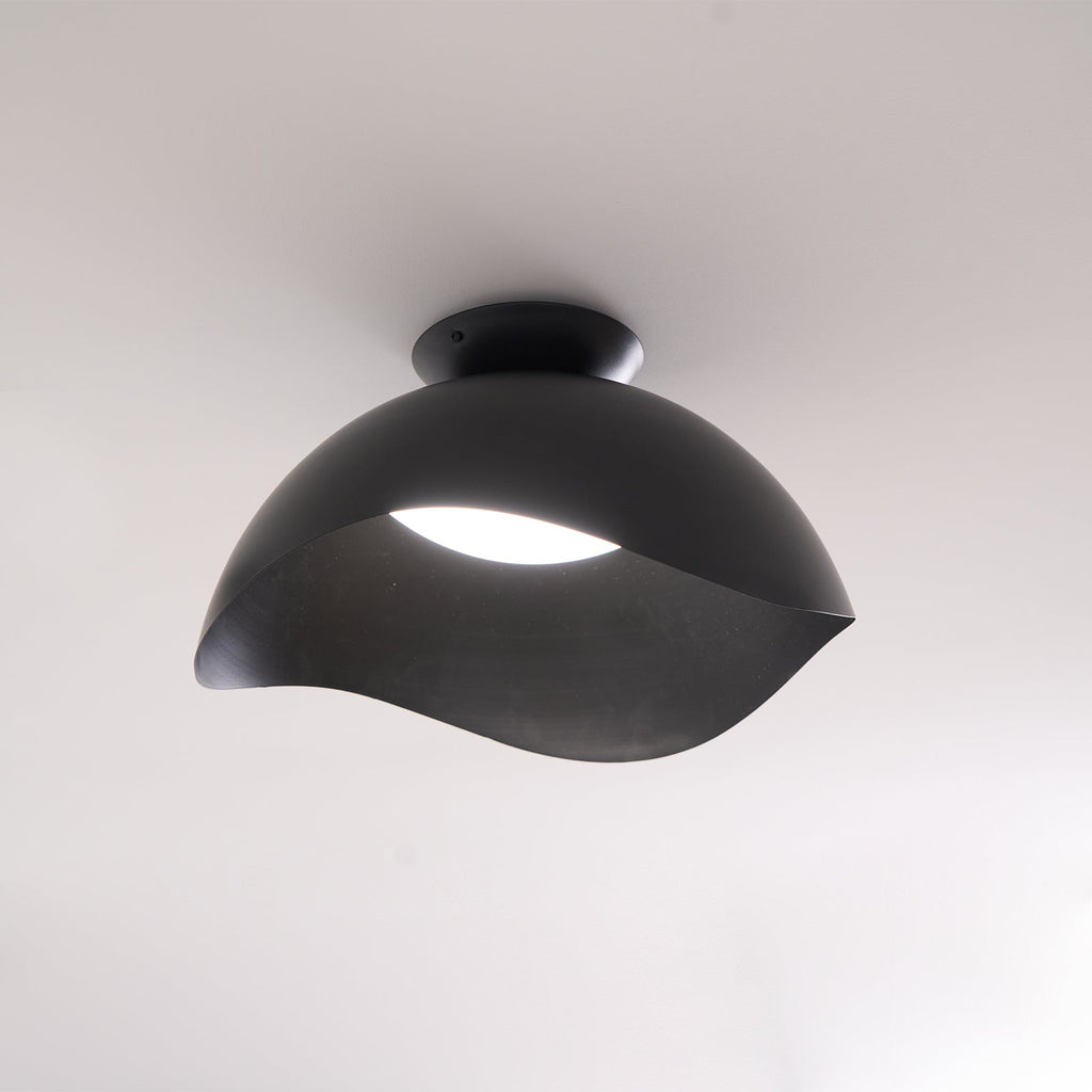 In black, this Clérachic ceiling light hangs in a softly lit room, its dome-shaped canopy catching ambient light.