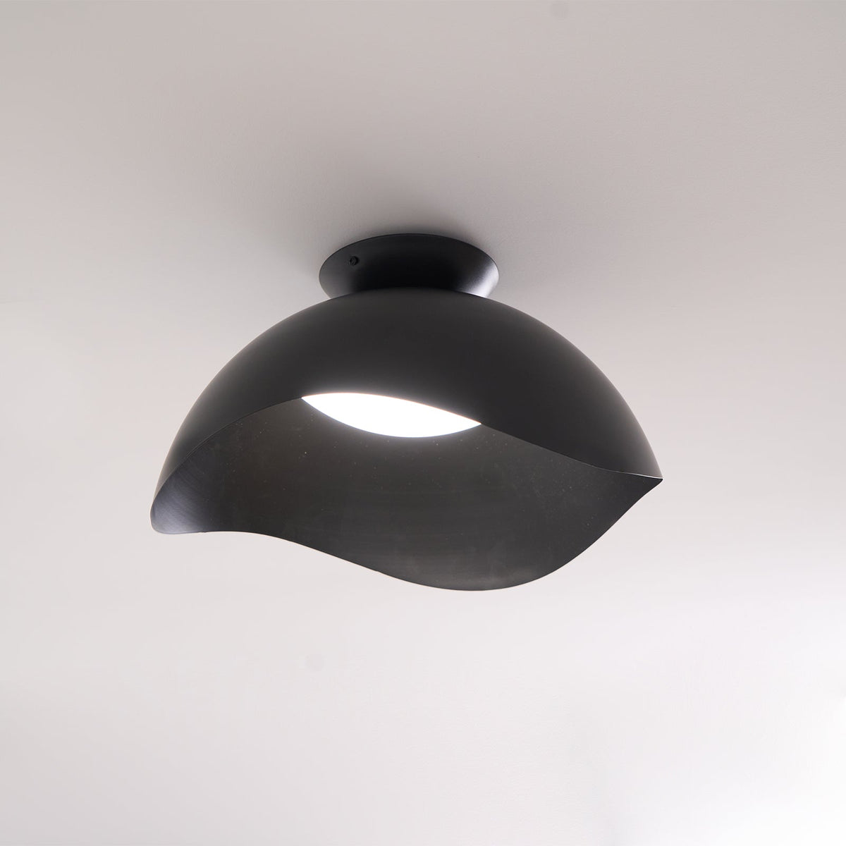In black, this Clérachic ceiling light hangs in a softly lit room, its dome-shaped canopy catching ambient light.