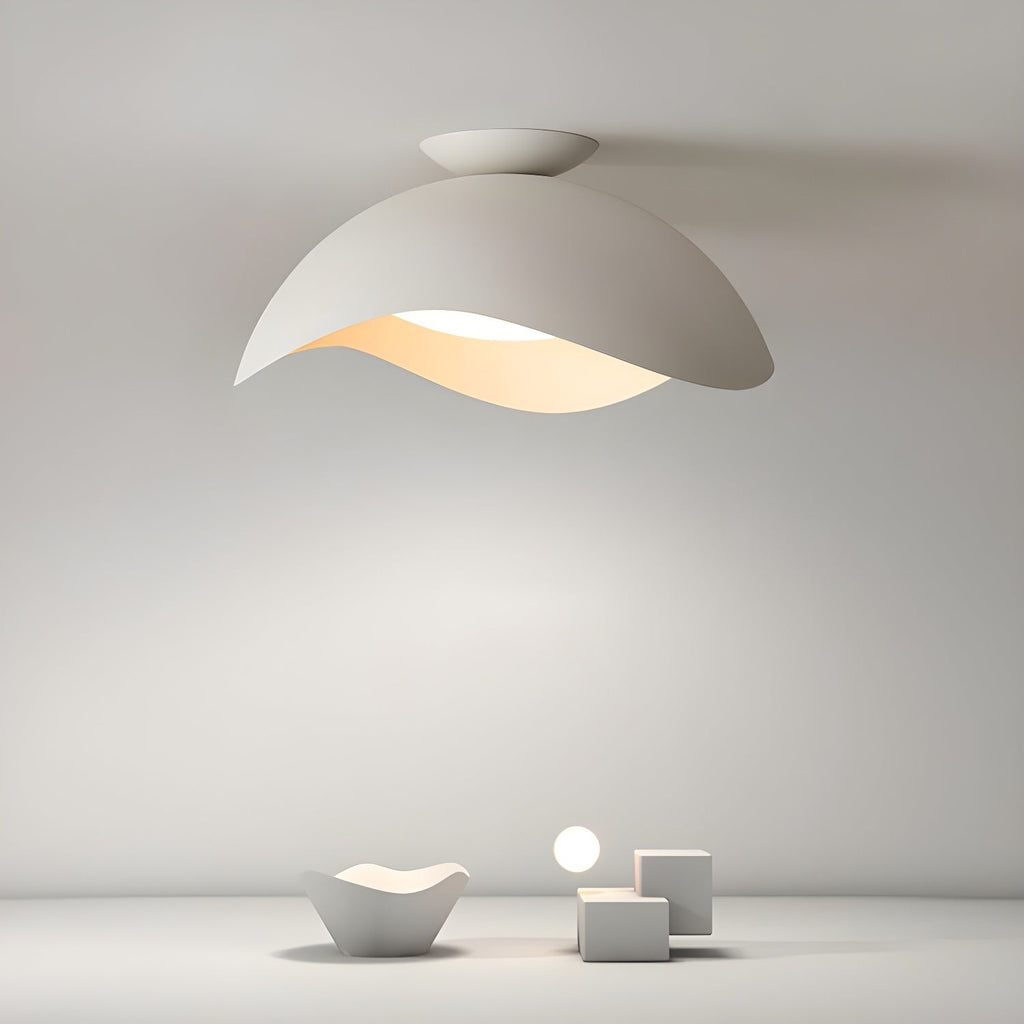 Sculptural white objects sit below this Clérachic ceiling light, which casts a soft glow across a plain grey wall.