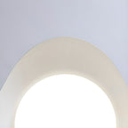 Close view of the curved wave opening on this Clérachic ceiling light, glowing bright white against the ceiling.