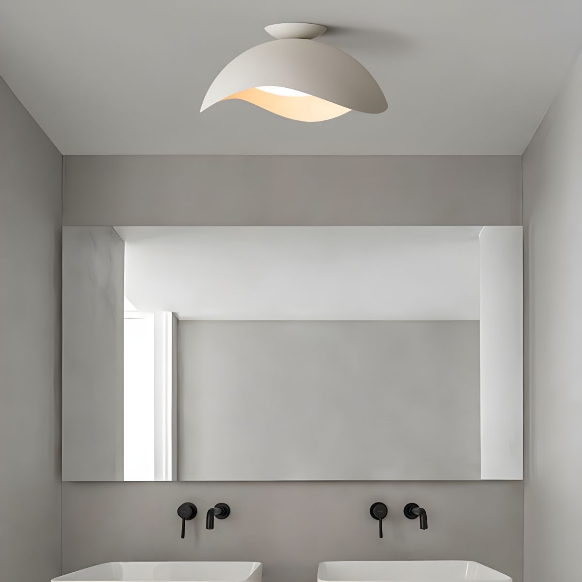 In a bathroom with a wide mirror and black fittings, the wave-shaped shade of this Clérachic light glows softly.