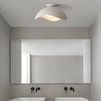 Fitted above a bathroom mirror with black wall taps, this Clérachic ceiling light hangs from a grey ceiling.