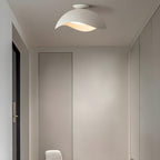 Mounted in a narrow hallway beside a dark door frame, this Clérachic wave ceiling light glows warm white.