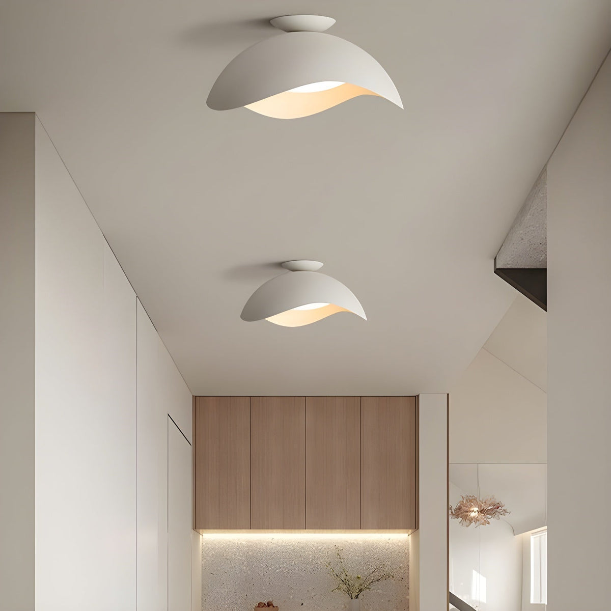 Two of this Clérachic wave ceiling light run down a hallway, leading toward a warmly lit kitchen beyond.
