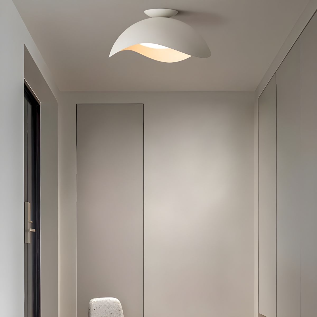 Fitted above a hallway corridor, this Clérachic wave ceiling light casts warm light onto closet doors nearby.