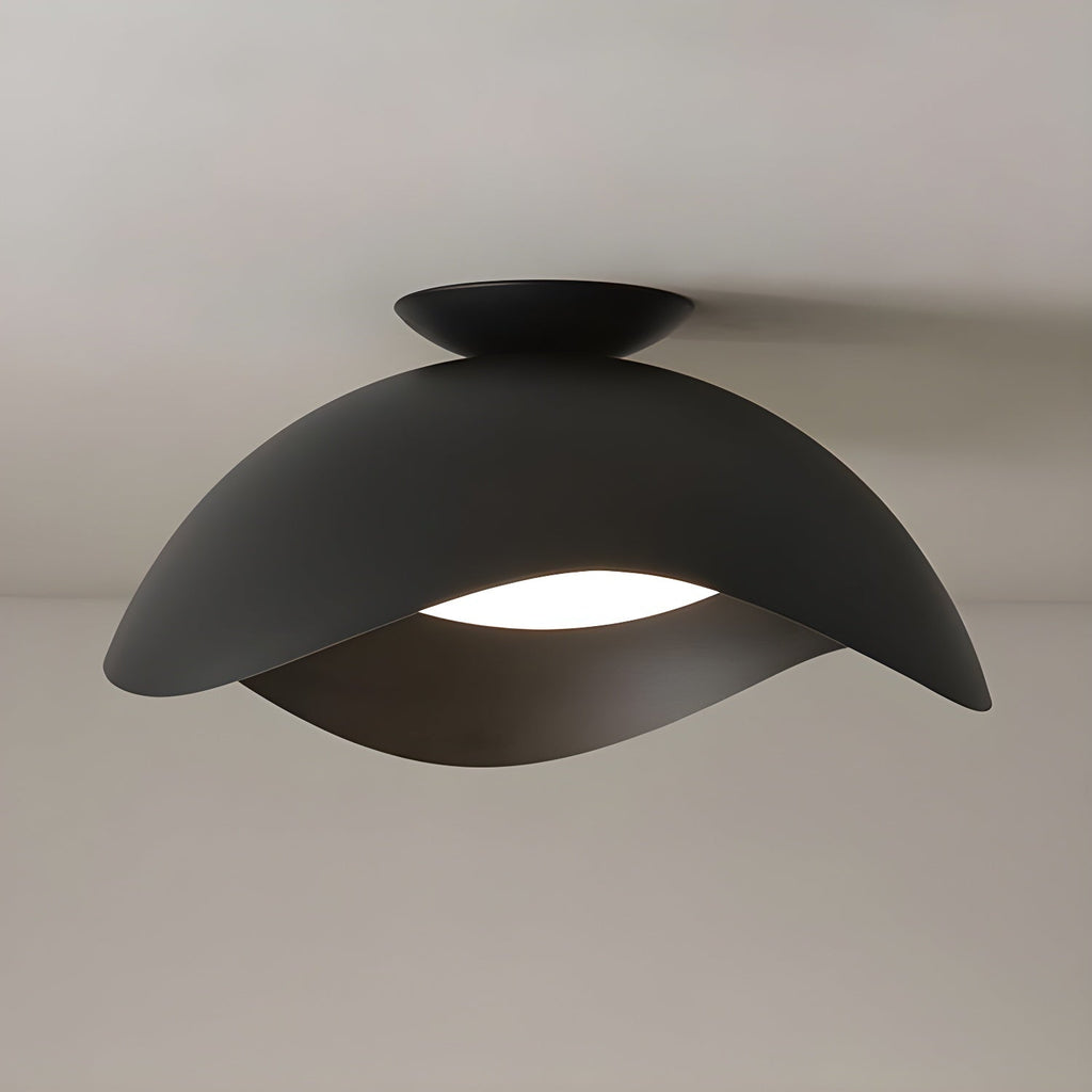 In black, this Clérachic ceiling light's wave shade glows warm underneath against a soft beige backdrop.