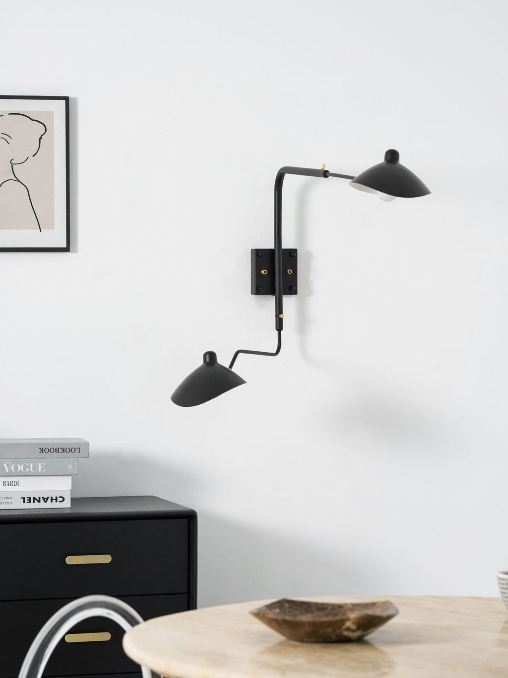 Long-arm wall sconce mounted beside artwork on a wall
