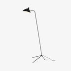 Sculptural black floor lamp beside an armchair and side table