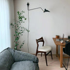 Wall sconce with slim black arm against a bright wall