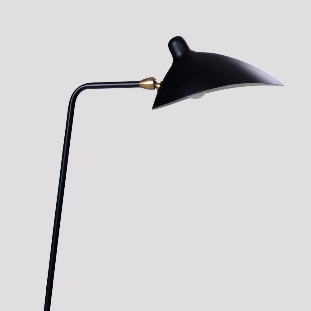 Black floor lamp arm and shade lit with a warm bulb
