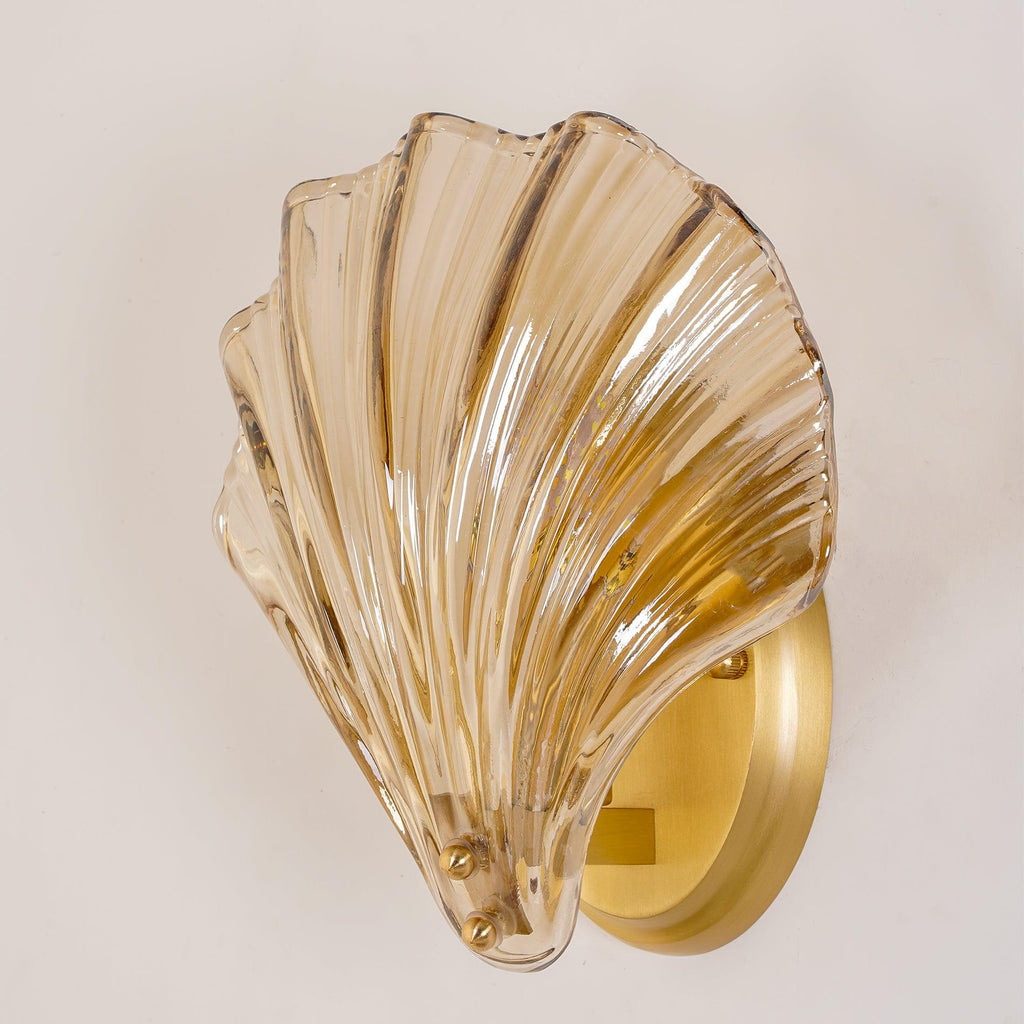 A closer angled view shows the ribbed amber glass shell and brass plate of this Clérachic wall light.