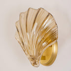 A closer angled view shows the ribbed amber glass shell and brass plate of this Clérachic wall light.