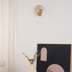 Glowing again above the same side table, vase and arched print, this Clérachic wall light is seen from a tighter angle.
