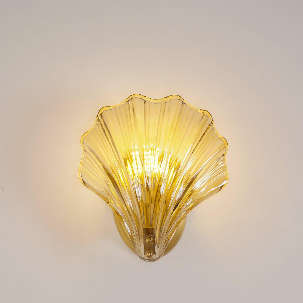 This Clérachic wall light's amber glass shell glows warmly against a plain white backdrop, seen straight on.
