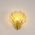 This Clérachic wall light's amber glass shell glows warmly against a plain white backdrop, seen straight on.