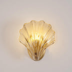 Shown front-on again, this Clérachic wall light's amber glass shell glows against a plain backdrop.