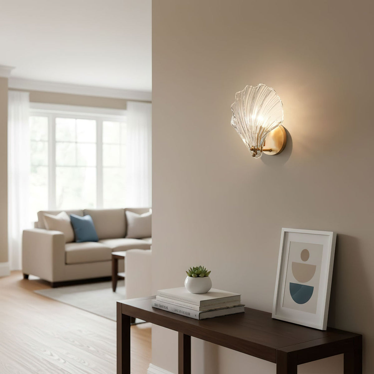 In a living room with a blue-cushioned sofa and a console table of books, this Clérachic wall light glows on a pale wall.