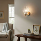 Beside a console table with books, a small plant and a framed print, this Clérachic wall light glows in a cream living room.