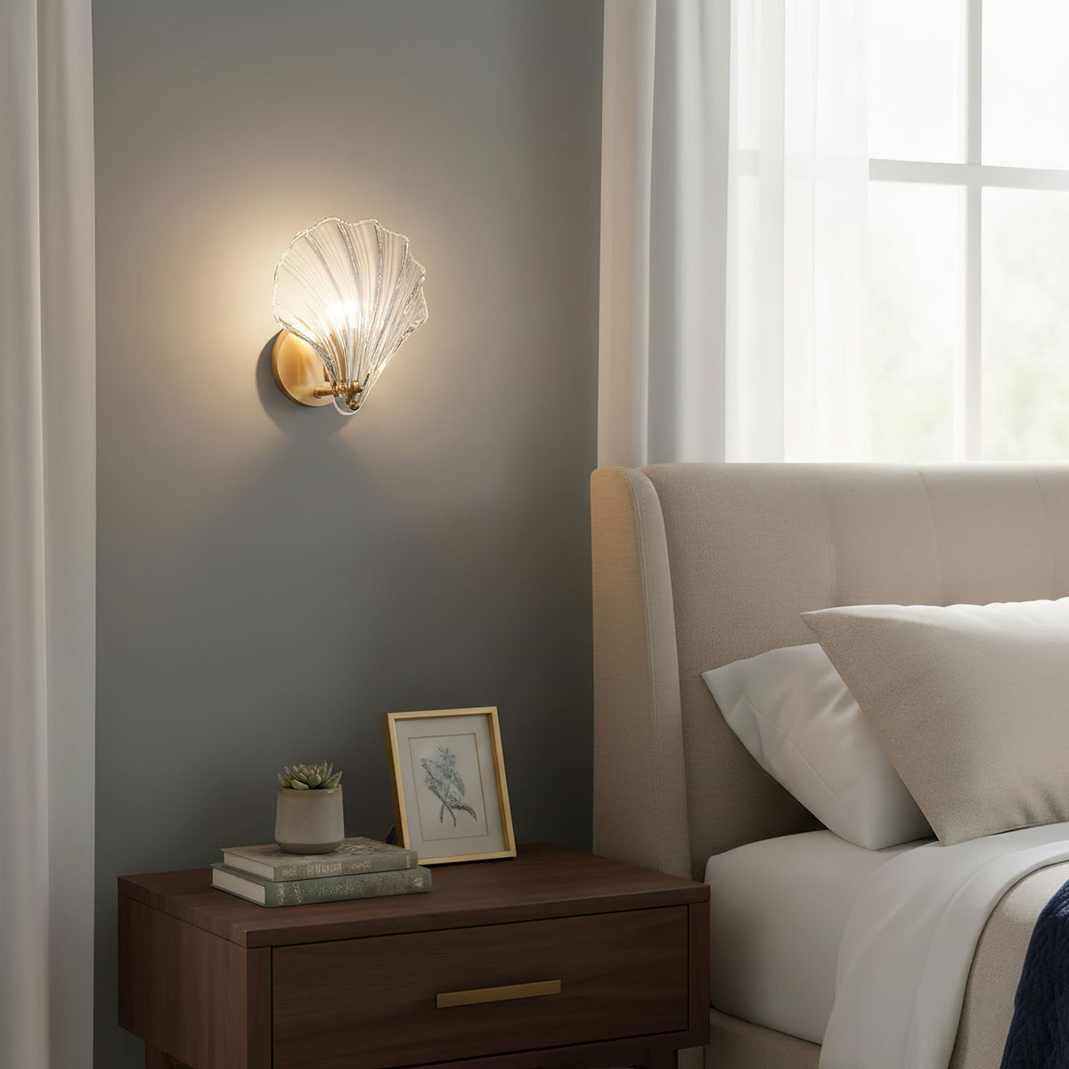 Above a wood nightstand holding a framed photo and a small succulent, this Clérachic wall light glows near a bed.