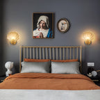 This Clérachic wall light is shown in a pair, flanking a framed portrait above a metal bed dressed in rust and grey linens.