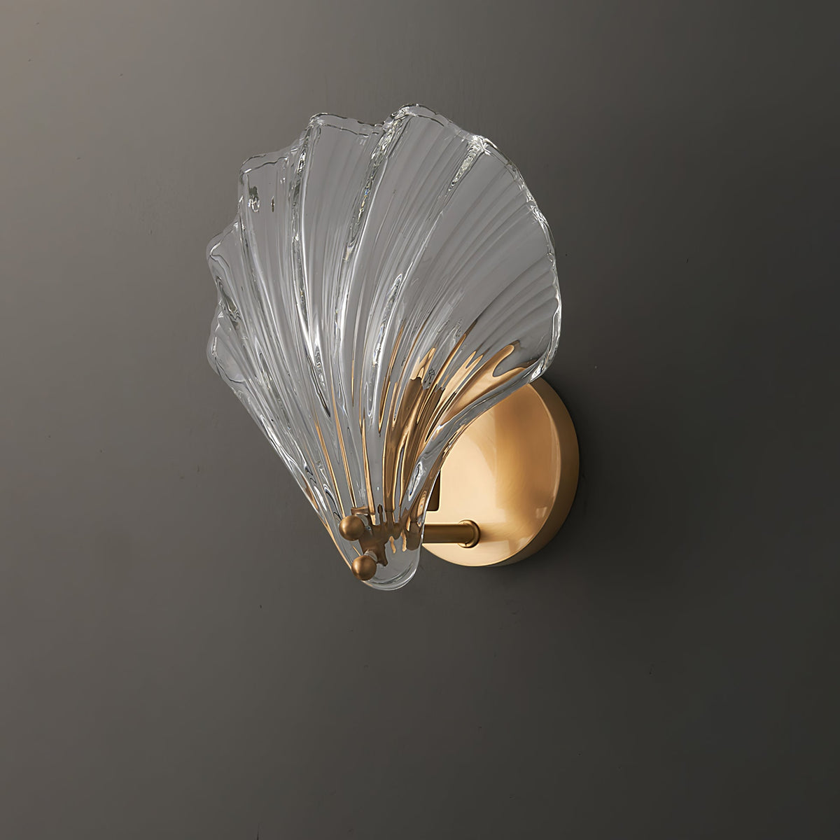 Photographed from the side against a dark backdrop, the pale glass shell of this Clérachic wall light glows brightly.