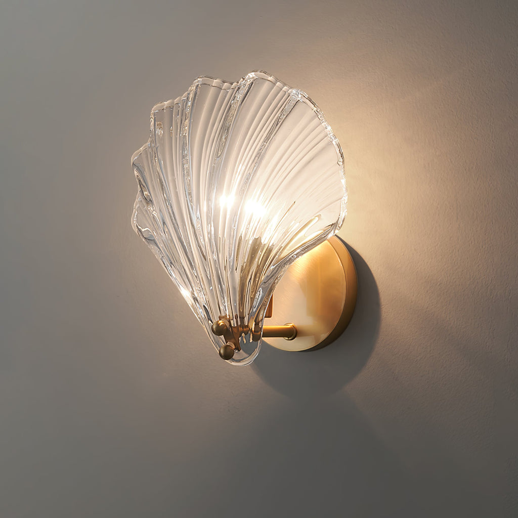 Seen from the side with a cast shadow, the clear glass shell of this Clérachic wall light glows on a grey wall.