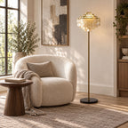 Layered art and a potted olive tree flank this Clérachic floor lamp, its shade lit warmly.
