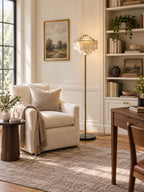 Beside a built-in bookshelf, this Clérachic floor lamp stands next to a cream armchair with a folded throw.
