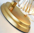 Close view from below shows the brass backplate and fixing screws behind the glass shell of this Clérachic wall light.