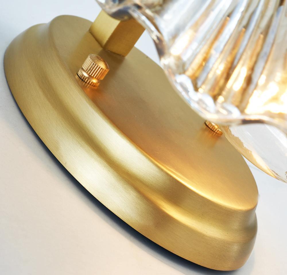 Close view from below shows the brass backplate and fixing screws behind the glass shell of this Clérachic wall light.