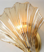A close angled view shows the ribbed texture and brass mount of this Clérachic wall light's glowing amber shell.
