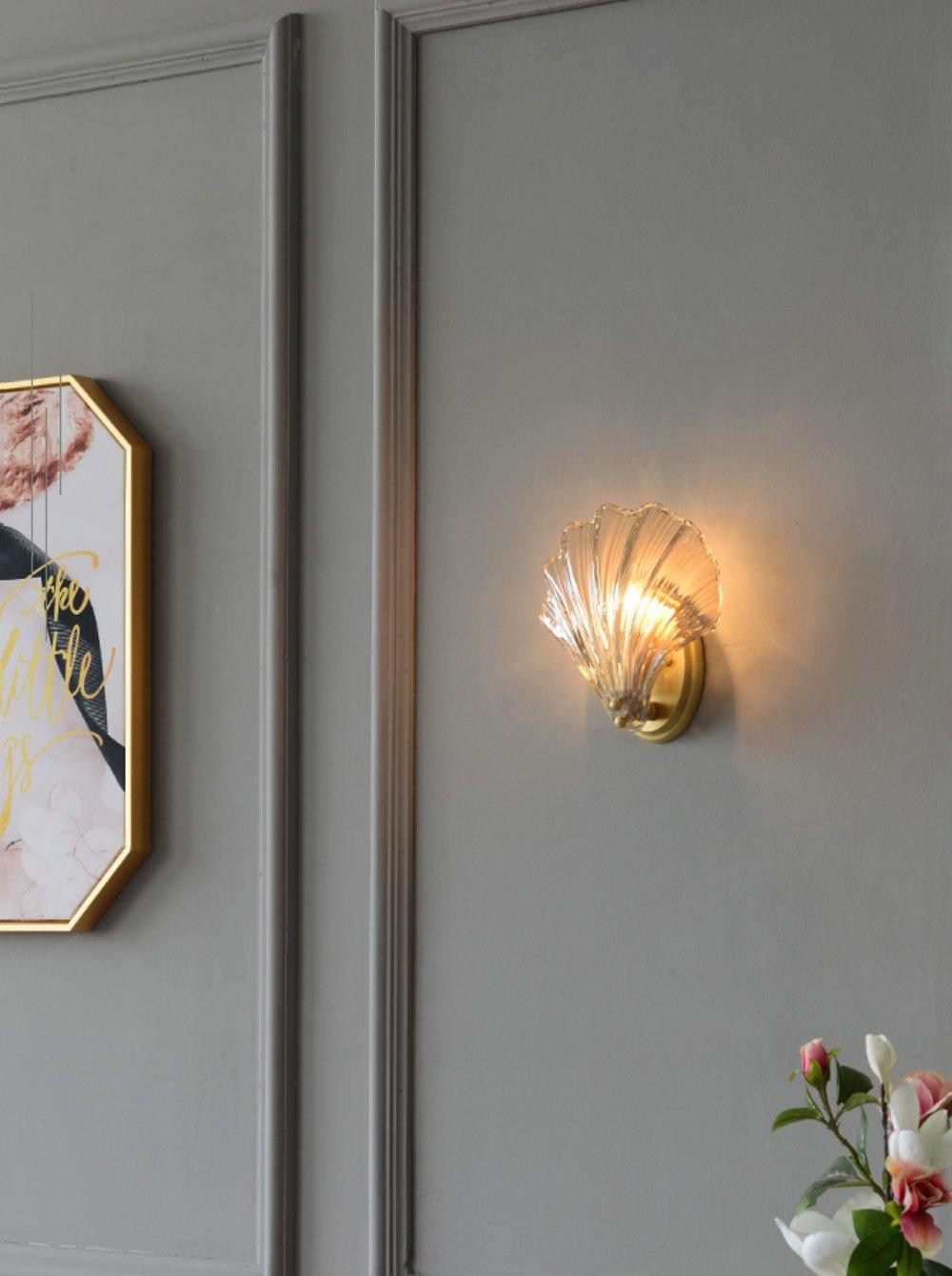 Beside a gold-framed print and pink orchid blooms, this Clérachic wall light glows on a grey panelled wall.