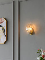 Beside a gold-framed print and pink orchid blooms, this Clérachic wall light glows on a grey panelled wall.