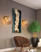 This Clérachic wall light appears in a pair, flanking an abstract print beside a leather armchair and a potted plant.