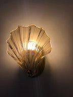 Against a near-black backdrop, the amber glass shell of this Clérachic wall light glows brightly, casting light upward.