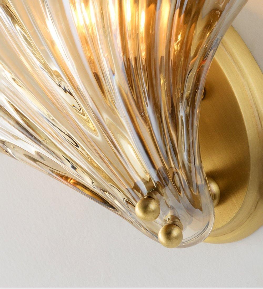 Close view of the ribbed amber glass and brass ball feet at the base of this Clérachic wall light.
