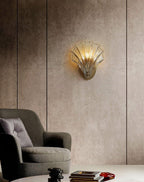On a textured bronze wall beside an armchair and coffee table, this Clérachic wall light glows warmly.